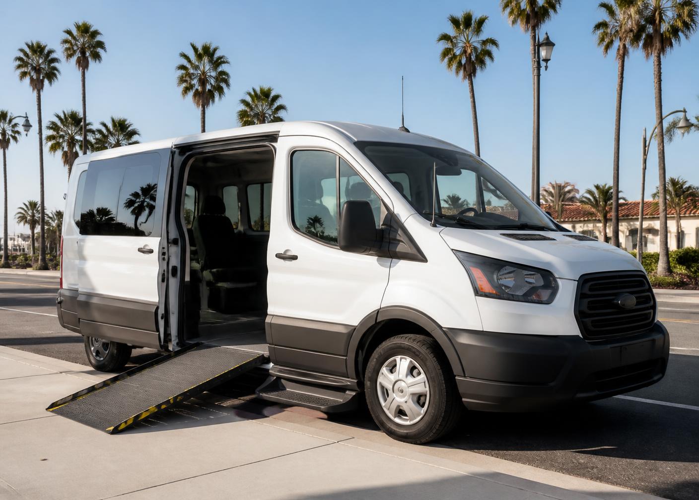 Wheelchair-accessible passenger van with its ramp deployed on a palm-lined street